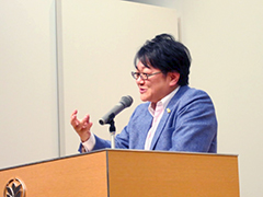 右手を上げながら講演する仲野塾長